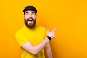 Cheerful happy bearded man in yellow tshirt pointing away and screaming