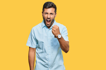 Handsome hispanic man wearing casual clothes angry and mad raising fist frustrated and furious while shouting with anger. rage and aggressive concept.