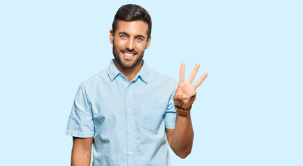 Handsome hispanic man wearing casual clothes showing and pointing up with fingers number three while smiling confident and happy.