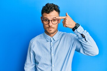 Young hispanic man wearing casual clothes and glasses pointing unhappy to pimple on forehead, ugly...