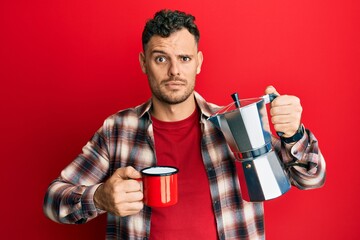 Young hispanic man drinking italian coffee skeptic and nervous, frowning upset because of problem. negative person.