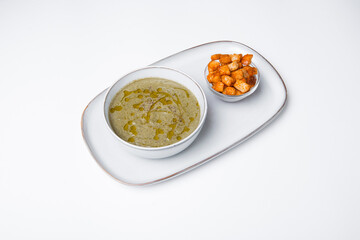 Photo of bowl creme soup with spinach and vegetables and some crackers