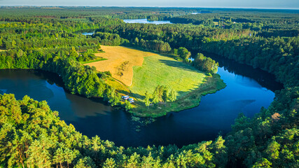 Curvy river between forests in summer, aerial view of Poland