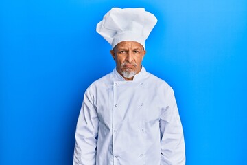 Middle age grey-haired man wearing professional cook uniform and hat depressed and worry for distress, crying angry and afraid. sad expression.