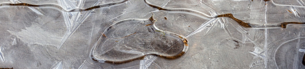 Close up of wide panorama of ice over a mud puddle for frosty background