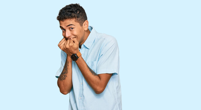 Young handsome african american man wearing casual clothes laughing nervous and excited with hands on chin looking to the side