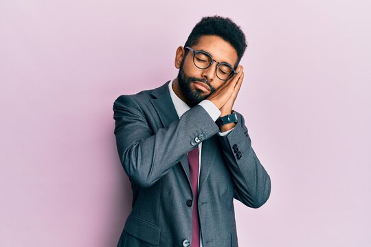 Handsome hispanic business man with beard wearing business suit and tie sleeping tired dreaming and posing with hands together while smiling with closed eyes.