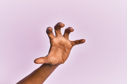 Arm And Hand Of Black Middle Age Woman Over Pink Isolated Background Grasping Aggressive And Scary With Fingers, Violence And Frustration