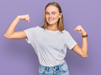 Obraz premium Beautiful young blonde woman wearing casual white t shirt showing arms muscles smiling proud. fitness concept.