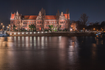 Wroclaw National Museum on the Odra River, night view from the shore.