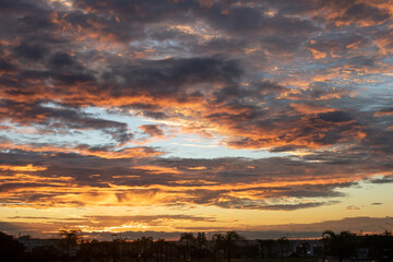 Black and orange  cotton-textured clouds spread across a blue sky to the horizon