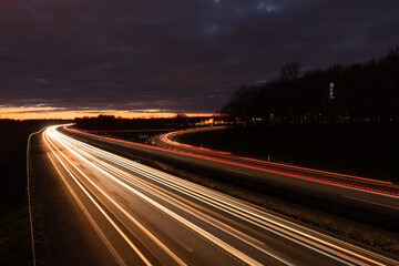 Autobahn bei Nacht mit fahrenden Autos. Langzeitbelichtung mit dramatischen Himmel
