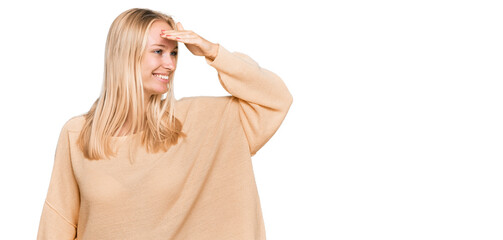 Fototapeta premium Young blonde girl wearing casual clothes very happy and smiling looking far away with hand over head. searching concept.