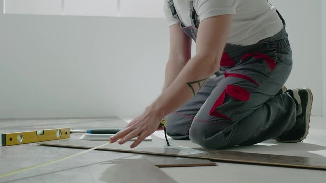 Handyman measures floor part with parquet boards in room