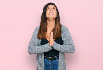 Beautiful hispanic woman wearing casual clothes begging and praying with hands together with hope...