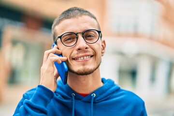 Young hispanic man smiling happy talking on the smartphone at the city.