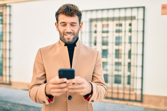 Handsome business man wearing elegant jacket using smartphone smiling happy outdoors