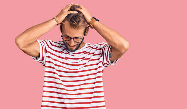 Handsome blond man with beard wearing casual clothes and glasses suffering from headache desperate and stressed because pain and migraine. hands on head.