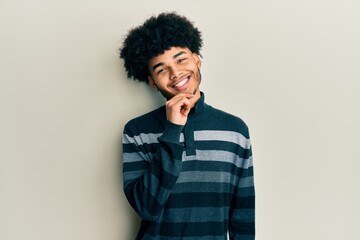 Obraz na płótnie Canvas Young african american man with afro hair wearing casual clothes looking confident at the camera with smile with crossed arms and hand raised on chin. thinking positive.