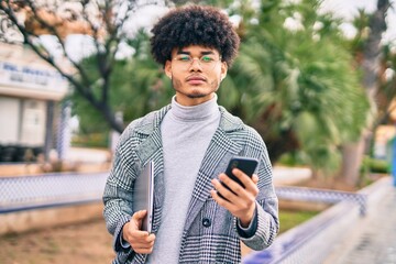 Fototapeta premium Young african american businessman with serious expression using smartphone at the city.