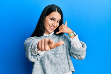 Young hispanic woman wearing casual clothes smiling doing talking on the telephone gesture and...