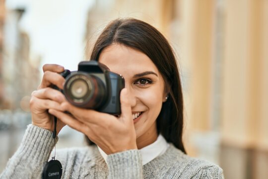 Young hispanic woman smiling happy using camera at the city.