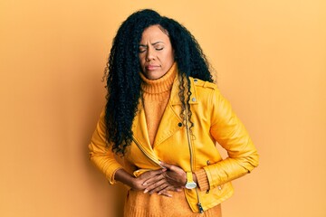 Middle age african american woman wearing wool winter sweater and leather jacket with hand on stomach because indigestion, painful illness feeling unwell. ache concept.
