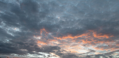 Fototapeta na wymiar White and orange cotton-textured clouds spread across a blue sky to the horizon