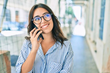 Young hispanic businesswoman smiling happy talking on the smartphone at the city.