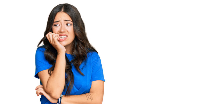 Beautiful brunette young woman wearing casual clothes looking stressed and nervous with hands on mouth biting nails. anxiety problem.