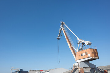 Shipyard cranes or portal cranes at logistic river harbour port against blue sky.