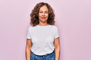 Middle age beautiful woman wearing casual t-shirt standing over isolated pink background with a...