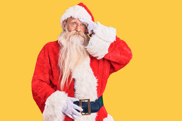 Old senior man with grey hair and long beard wearing traditional santa claus costume worried and stressed about a problem with hand on forehead, nervous and anxious for crisis