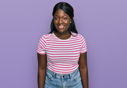 African young woman wearing casual striped t shirt with a happy and cool smile on face. lucky person.
