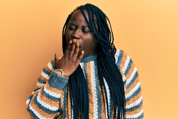 Young black woman with braids wearing casual winter sweater bored yawning tired covering mouth with hand. restless and sleepiness.