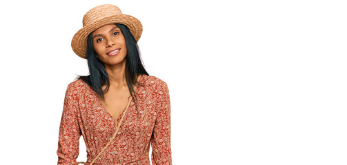 Young african american woman wearing summer hat relaxed with serious expression on face. simple and natural looking at the camera.