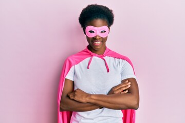Young african american girl wearing superhero mask and cape costume happy face smiling with crossed arms looking at the camera. positive person.