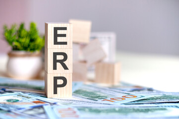 wooden cubes with the letters ERP arranged in a vertical pyramid on banknotes, business concept