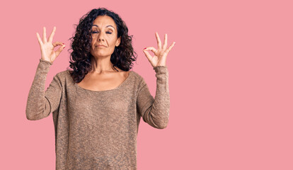 Middle age beautiful woman wearing casual sweater relax and smiling with eyes closed doing meditation gesture with fingers. yoga concept.