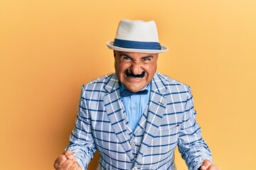 Mature middle east man with mustache wearing vintage and elegant fashion style very happy and excited doing winner gesture with arms raised, smiling and screaming for success. celebration concept.