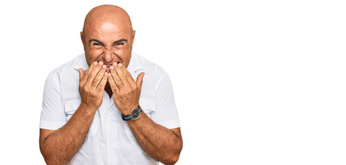 Mature middle east man with mustache wearing casual white shirt laughing and embarrassed giggle...