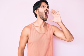 Handsome hispanic man wearing casual clothes shouting and screaming loud to side with hand on mouth. communication concept.