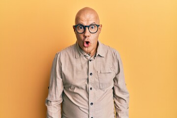 Middle age bald man wearing casual clothes and glasses afraid and shocked with surprise expression, fear and excited face.