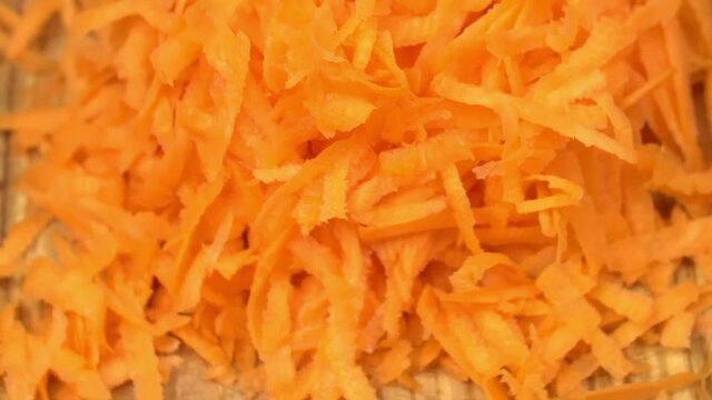 Grated carrot extremely close-up rotates very slowly on the cutting board. stock footage
