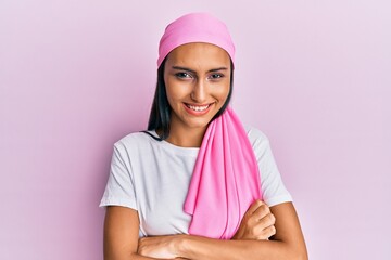 Young brunette woman wearing breast cancer support pink scarf happy face smiling with crossed arms looking at the camera. positive person.