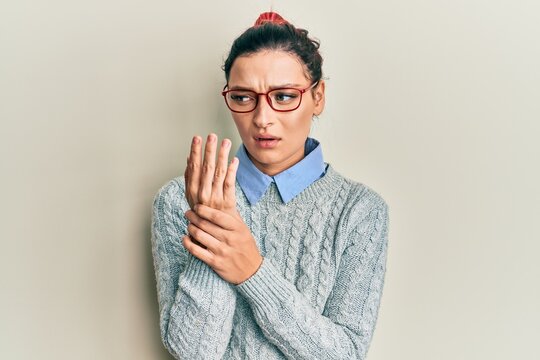 Young caucasian woman wearing casual clothes and glasses suffering pain on hands and fingers, arthritis inflammation