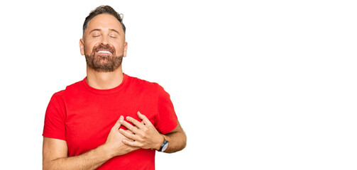 Handsome middle age man wearing casual red tshirt smiling with hands on chest with closed eyes and grateful gesture on face. health concept.