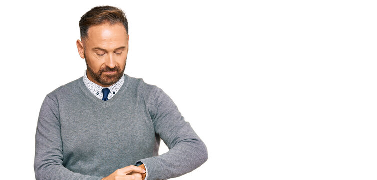 Handsome middle age man wearing business clothes checking the time on wrist watch, relaxed and confident