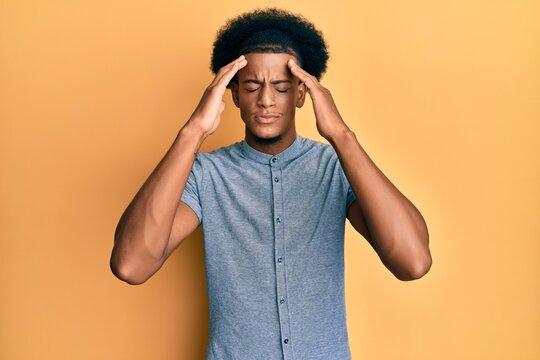 African american man with afro hair wearing casual clothes with hand on head, headache because stress. suffering migraine.