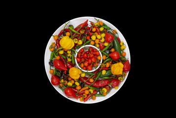 Mix of colorful peppers in round dish with black background top view